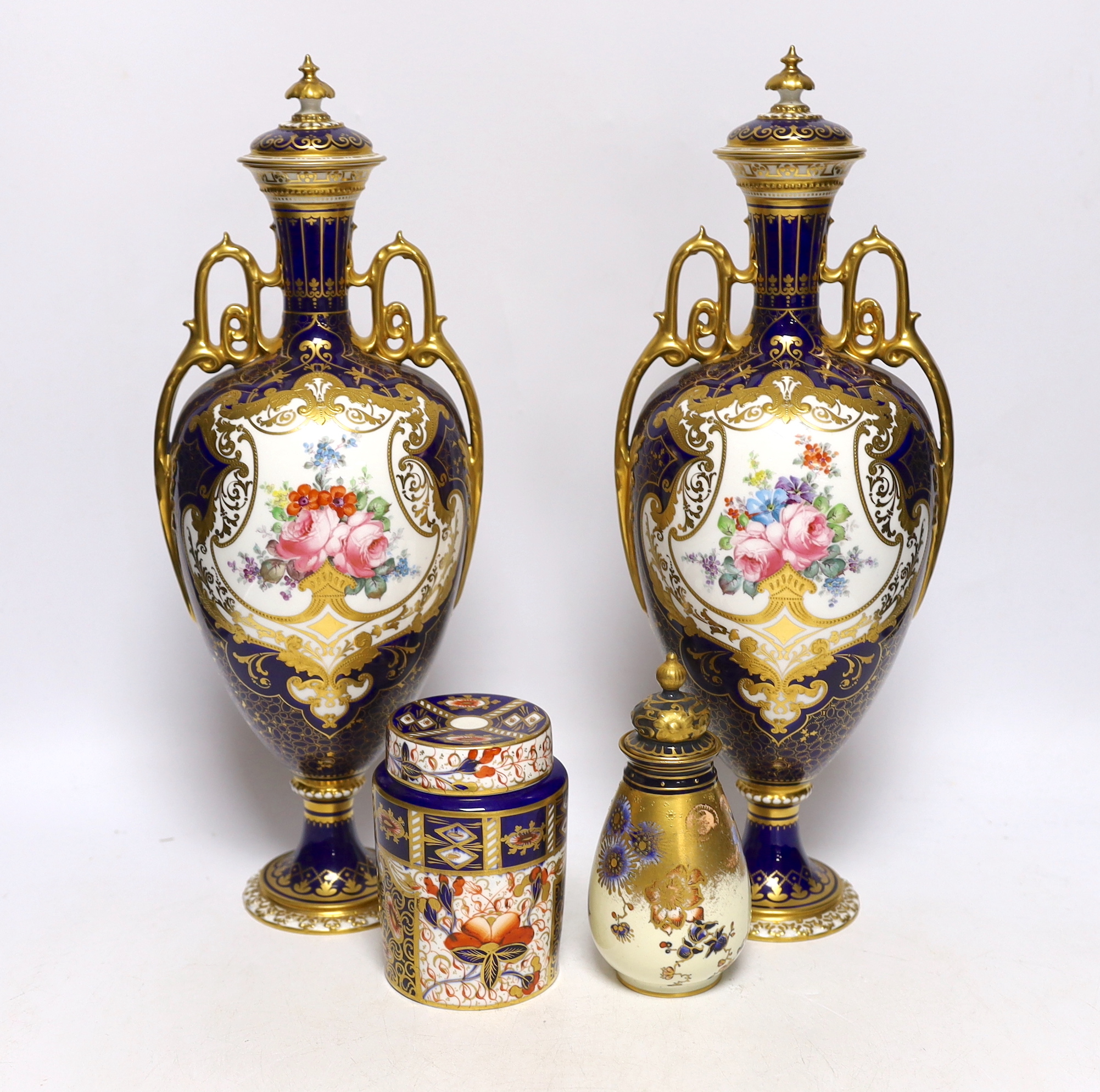 A pair of Royal Crown Derby porcelain urns and covers together with a smaller example and an Imari style jar and cover, 36cm high